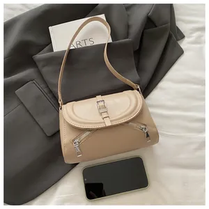 Detail of beige faux leather shoulder bag with magnetic flap and metal buckle accents