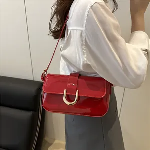Glossy red patent leather shoulder bag with silver horseshoe buckle and adjustable strap