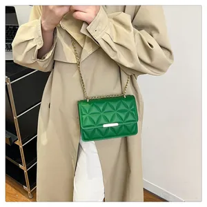 Close-up of bright green quilted square crossbody bag with gold chain strap on beige coat