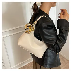 Close-up of white lychee leather tote bag with a decorative silk scarf on the strap