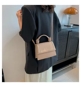 Dettaglio della borsa a tracolla beige minimalista con manico a nodo e pelle sintetica liscia