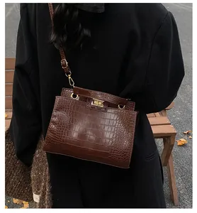 Gros plan sur la texture crocodile marron et le fermoir tournant doré du sac à main chic