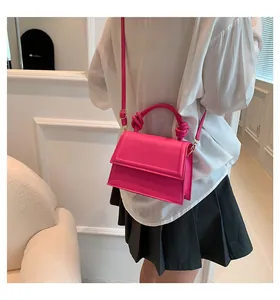 Dettaglio borsa a tracolla magenta con manico a nodo e accessori in metallo dorato