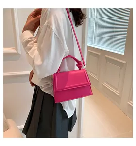 Dettaglio mini borsa quadrata rosso rosa con manico annodato unico e tracolla sottile