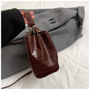 Gros plan sur la texture crocodile marron foncé et les anneaux dorés du sac à main
