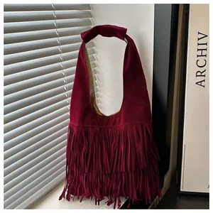 Dettaglio borsa scamosciata bordeaux scuro con frange e ombre di luce naturale filtrata