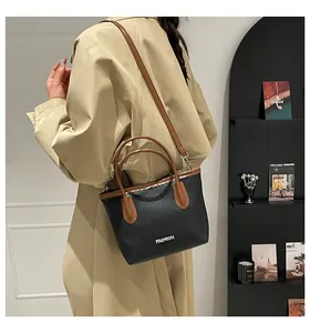 Détail d'un sac seau noir minimaliste avec anses marron et lettrage argenté de mode