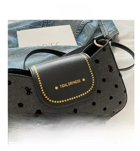 Close-up of gray herringbone fabric with black velvet dots and bow on the crossbody bag