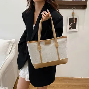 Minimalist cream canvas and brown leather contrast tote bag held by model for daily wear
