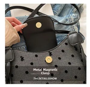 Detail of grey herringbone bag with black polka dots, mini bows and gold magnetic buckle