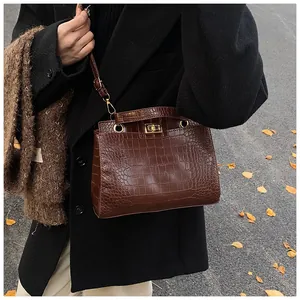 Détail du sac à main marron à motif crocodile avec fermoir rotatif doré élégant
