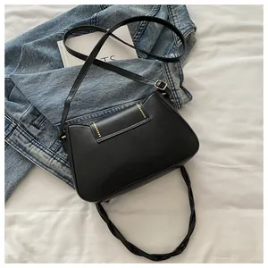 Detail of black crossbody bag with yellow dot accents and adjustable leather strap