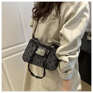 Detail of black polka dot shoulder bag with Tidal Dryness logo and twisted handle