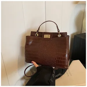 Détail du sac à main marron foncé effet crocodile avec fermoir doré et poignée fixe