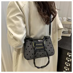 Detail of grey denim bag with polka dots, bow embroidery and black leather strap
