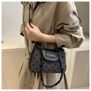 Close-up of retro polka dot baguette bag with metal studs and textured woven strap