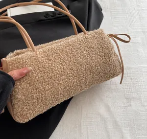 Close-up of beige lamb wool fabric and leather handle detail on the plush shoulder bag