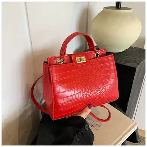 Détail d'un sac à main rouge à motif crocodile avec fermoir doré et poignée élégante