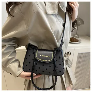 Detail of grey polka dot crossbody bag with leather flap and decorative side bows