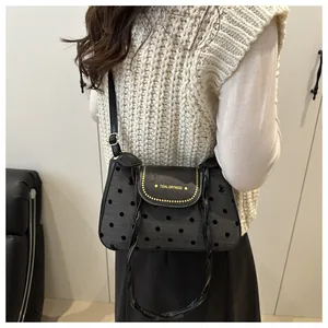 Close-up of small shoulder bag featuring black polka dots and gold brand lettering logo
