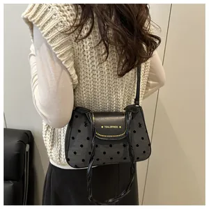 Detail view of a retro polka dot underarm bag with gold rivets and TIDAL DRYNESS text