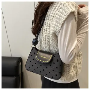Close-up of black polka dot shoulder bag with Tidal Dryness text on a minimalist model