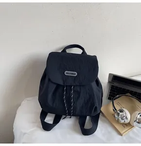 Close-up of black nylon backpack detail featuring drawstring closure and logo brand tag
