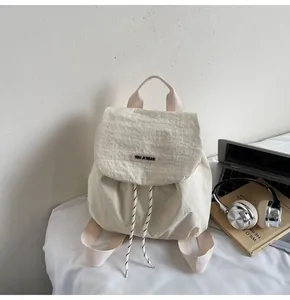 Detail of cream nylon backpack with You Ji Bear logo and drawstring flap closure