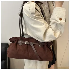 Detail of dark brown suede shoulder bag with metallic buckle worn with elegant trench coat