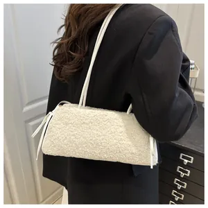 Detailed texture of white faux shearling shoulder bag on a model wearing black blazer