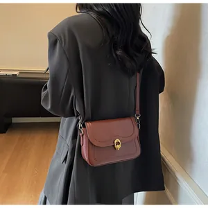 Retro reddish-brown square crossbody bag with gold buckle on a model in a black suit