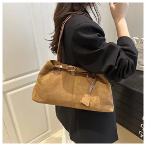 Close-up of brown faux suede tote bag with leather strap and decorative square tag