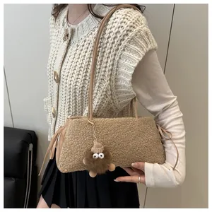 Detail of plush lamb wool mini phone bag with a cute brown monster charm and leather strap