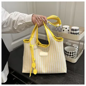 Close-up of yellow and white striped canvas tote bag with hand-held strap detail