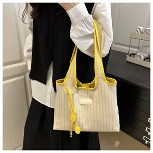 Detail of yellow striped tote bag showing fine woven texture and decorative leather label