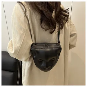 Detail of a 3D leopard head relief on a black leather crossbody bag with metal zippers