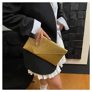 Detail of a metallic gold crocodile embossed clutch bag held by a fashion model