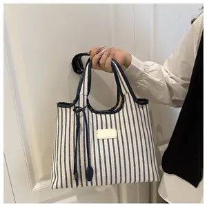 Close-up of blue and white striped canvas tote bag with dark blue leather trim details