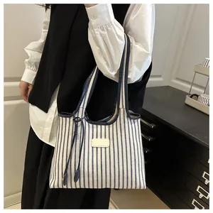 Detail of blue and white striped canvas tote bag with leather patch and sturdy handles