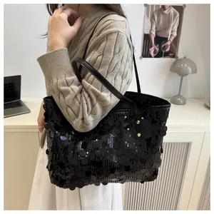 Detail of black sequin tote bag featuring metallic luster and leather shoulder strap
