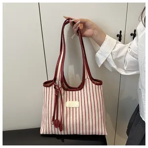 Detail of red striped canvas tote bag showing high-quality faux leather handles and trim
