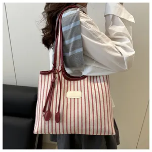 Detail of red striped canvas tote bag showing high-quality leather straps and textured fabric