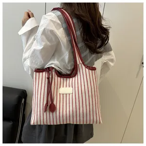 Detail of red and white striped canvas tote bag with smooth leather straps and fringe