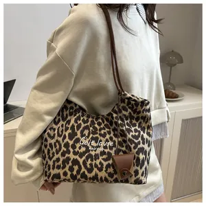 Vista detallada del bolso de lona con estampado de leopardo, correas marrones y letras