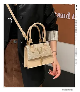 Detail of elegant beige crossbody bag featuring diamond-set flap and gold V-logo tassel