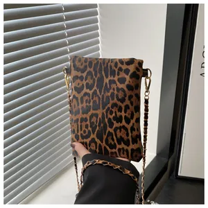 Detail of leopard print crossbody bag with gold hardware and woven metal chain strap