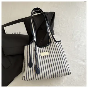 Detail of canvas tote bag with navy stripes, leather handles and artistic props