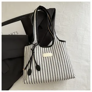 Detailed view of the striped canvas tote bag with premium leather trim and drawstring accents