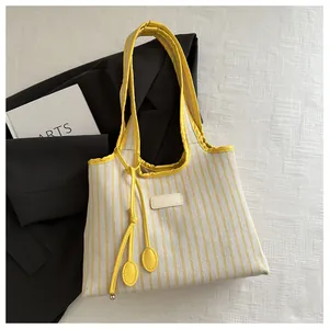 Flat lay of yellow striped canvas tote bag styled with a blazer and artsy magazine