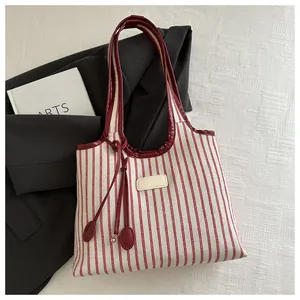 Detail of red and white striped tote bag with leather handles and decorative label tag